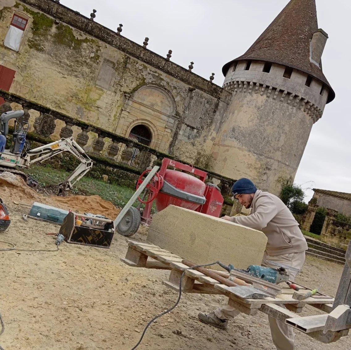 Compagnon d'Entreprise Berry taillant un bloc de pierre sur le chantier de restauration d'un château