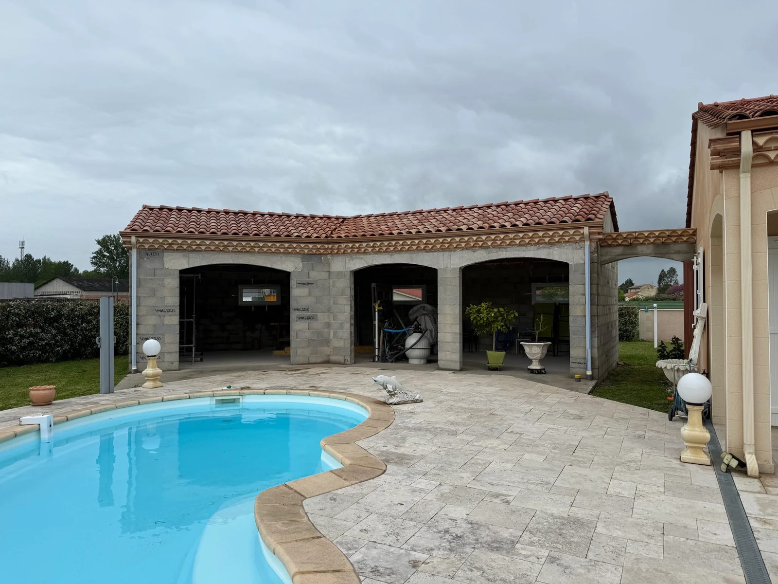 Pool house maçonné en blocs, arcades et toiture en tuiles canal
