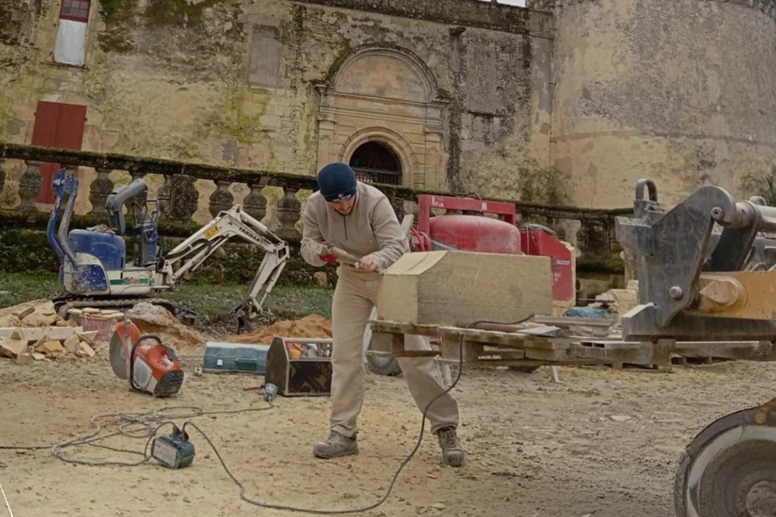 Tailleur de pierre d'Entreprise Berry dressant un bloc sur un chantier de château