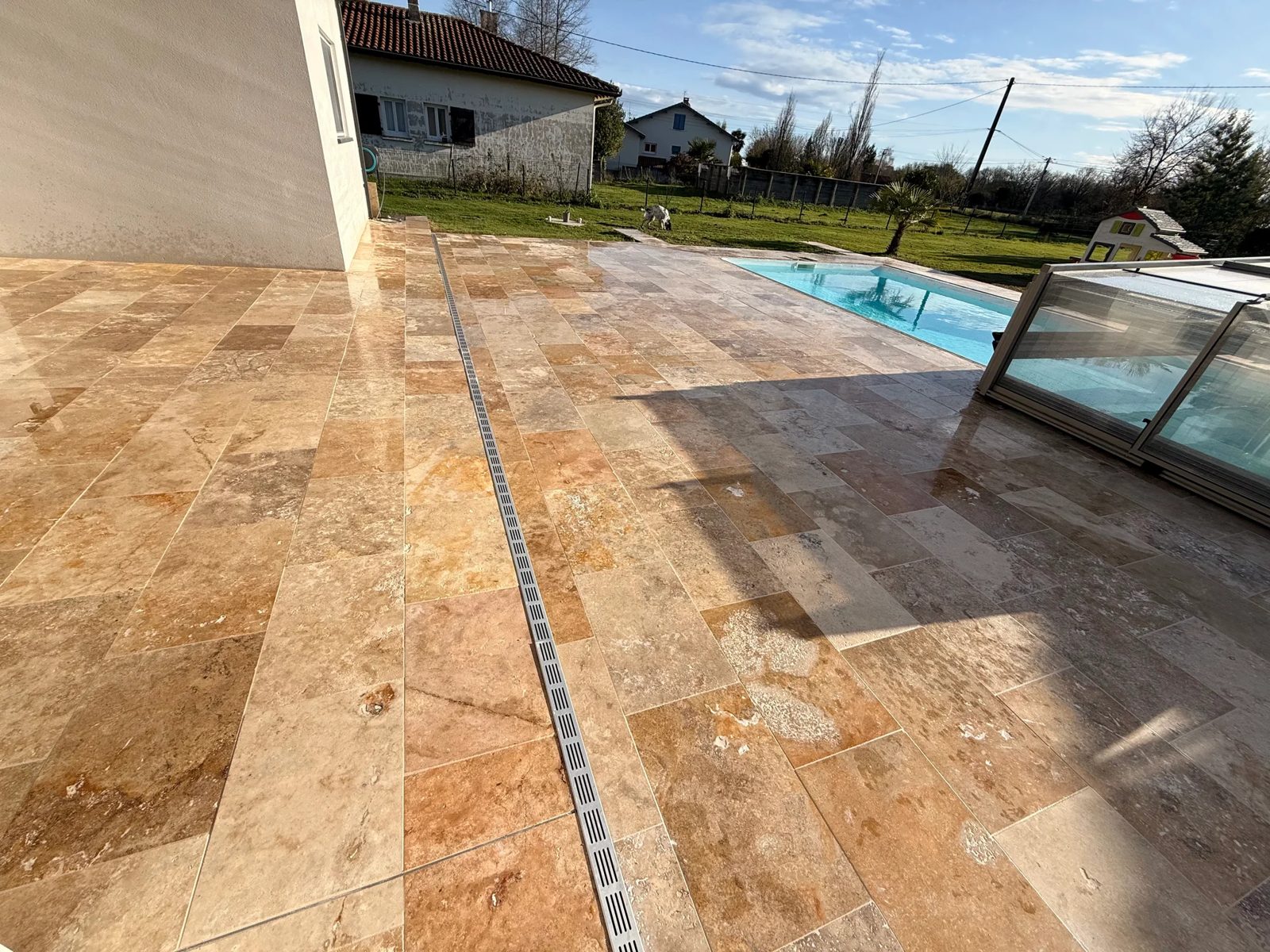 Terrasse en travertin réalisée par l'équipe Entreprise Berry autour d'une piscine